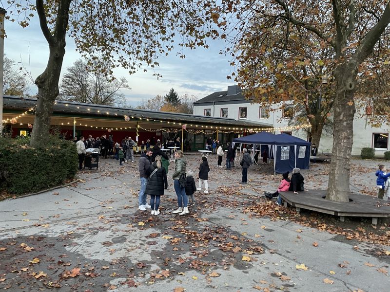Herbstfest: Familien auf dem Schulhof unter herbstlichen Bäumen
