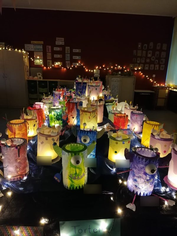 Viele bunt leuchtende Monsterlaternen mit großen Augen auf einem dunklen Tisch