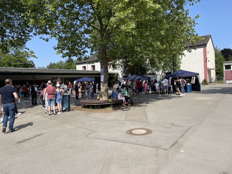 Sommerfest auf dem Schulhof mit Pavillons unter dem großen Baum
