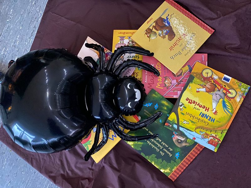 Bilderbücher und eine große schwarze Spinne aus Folie auf einem dunklen Tuch