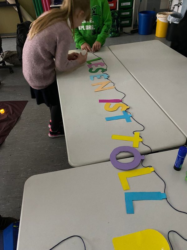 Zwei Kinder kleben bunte Buchstaben zum Schriftzug Lesen ist toll zusammen